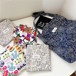 Canvas tote bags with floral patterns and oil painting prints on a minimalist white table