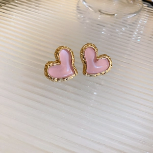 Dettaglio di orecchini a cuore in smalto rosa con cornice dorata ondulata su vetro