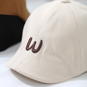 Minimalist beige cotton baby beret hat with a brown 3D embroidered letter W