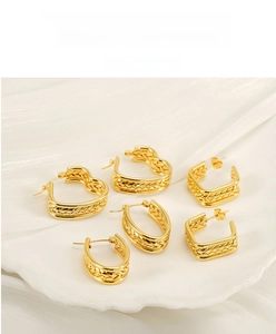 Détail de boucles d'oreilles en acier doré avec motifs cœur, ovale et carré en épis