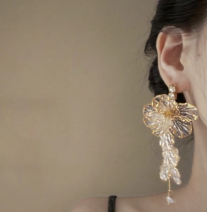 Detail of floral petal tassel earring with champagne gold accents and pearls on model