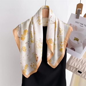 Elegant silk scarf with yellow lotus and butterfly prints hanging on a wooden hanger