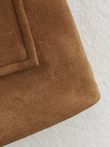 Vue macro détaillée montrant la texture riche du daim marron sur la poche d'une veste