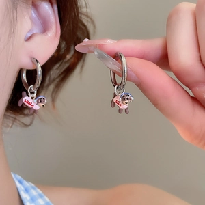 Detailed close-up of enamel dachshund dog charm earrings worn on ear with silver hoop