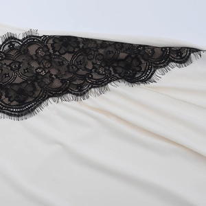 Detail of cream silk fabric with black lace trim on a V-neck slit vacation dress
