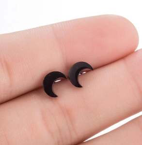 Macro shot of minimalist black moon stud earrings held between fingers for scale
