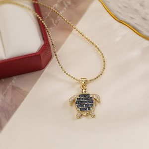 Detail of 18K gold plated sea turtle necklace with blue cubic zirconia and crystals