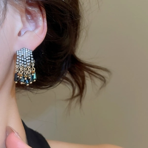 Detailed side view of a model wearing long vintage tassel earrings with zircon and pearls