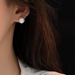Close-up of minimalist 8-10mm white freshwater pearl stud earring on model's ear
