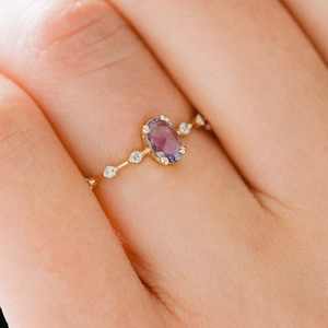 18k gold minimalist ring with oval purple zircon and accent diamonds worn on finger