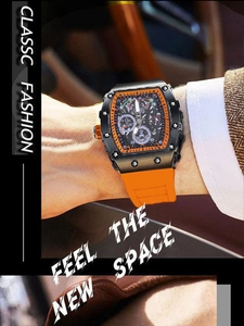 Detalle del reloj mecánico esqueleto de forma tonel con correa de caucho naranja en la muñeca