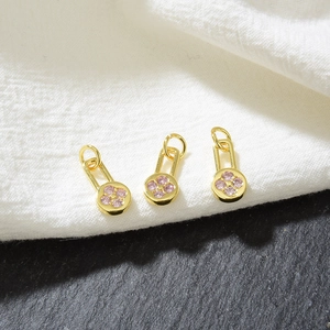 Macro detail of three gold flower pendants with pink cubic zirconia on a dual texture base