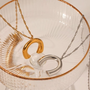 Detailansicht goldener und silberner U-förmiger Halsketten mit Wasserwellenkette im Glas