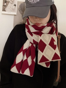 Détail d'une écharpe en maille à losanges rouge et blanc avec une casquette grise brodée