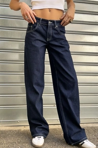 Gros plan sur un jean large taille haute bleu délavé avec surpiqûres blanches contrastées