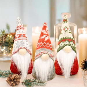 Three Christmas gnomes on wooden table with festive knitted hats and plush beards