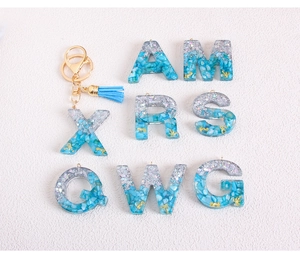 Detail of resin letter pendants with blue glitter gradient and gold seahorse charms