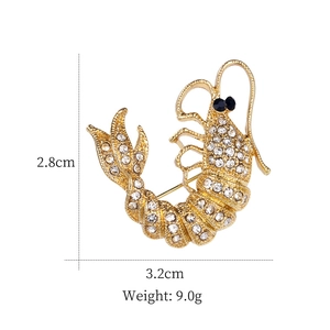 Broche crevette dorée avec cristaux, 2,8cm x 3,2cm, présentée sur un fond blanc neutre