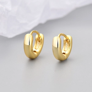 Macro shot of minimalist gold hoop earrings with polished finish and snap closure