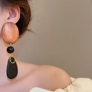 Detail of wooden drop earrings with black beads and gold links on model
