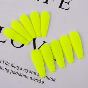 Detailed view of matte neon yellow coffin press-on nails on an artistic magazine background