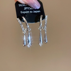 Macro detail of drop-shaped zircon earrings with dangling silver chain on display