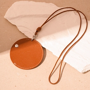 Close-up of orange leather round pendant with white stitching and metal snap button