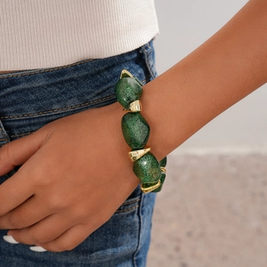 Close-up of green acrylic beads and gold geometric stones on a vintage style bracelet