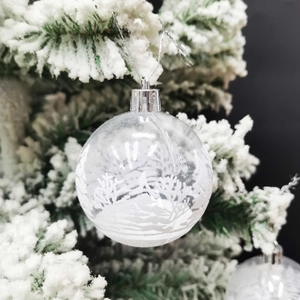 Boule de Noël transparente de 6cm avec décor de neige sur une branche de sapin enneigée