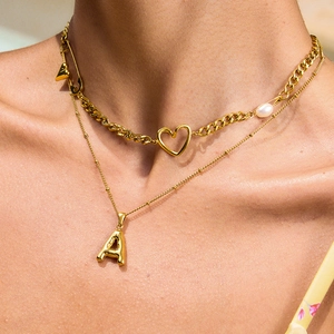 Dettaglio della collana a catena cubana dorata con pendente a cuore e perla su modella
