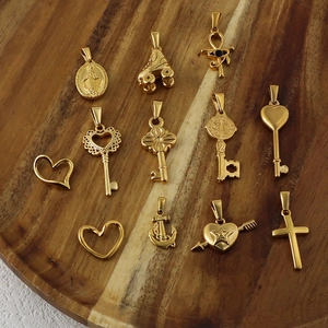 Collection de pendentifs variés en acier inoxydable doré sur un plateau en bois