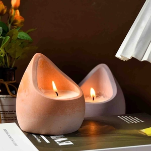 Tropfenförmige Silikonform für Duftkerzen mit orangefarbenen und violetten Haltern bei Licht
