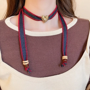 Detail of denim heart choker featuring striped ribbon and gold heart-shaped pendant