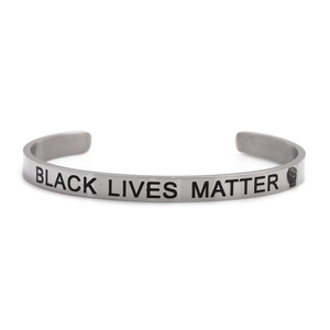 Close-up of silver steel cuff bracelet with Black Lives Matter engraving and fist symbol