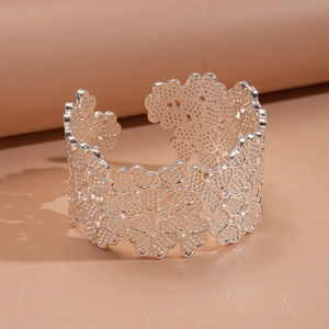 Vue détaillée du motif floral ajouré en argent sur un large bracelet jonc ouvert