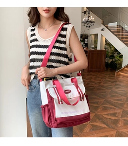 Detailed shot of a large white and burgundy shoulder bag with fashion logo and pink strap