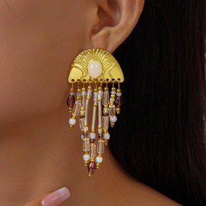 Detailed close-up of golden fringe tassel earrings with colorful beads on a model