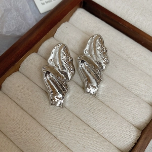 Detailed close-up of silver twisted earrings with irregular molten metal texture in a box
