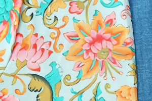Nahaufnahme von Blumendruck auf hellblauem Baumwollstoff mit orangefarbenen Blüten
