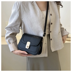 Detail shot of a black leather crossbody square bag featuring a gold twist lock closure
