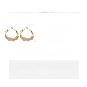 Macro detail of twisted golden hoop earrings with zircon stones and dimensions 3.5cm by 3cm