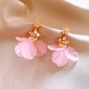 Macro detail of French flower drop earrings with pink resin petals and gold diamond accents