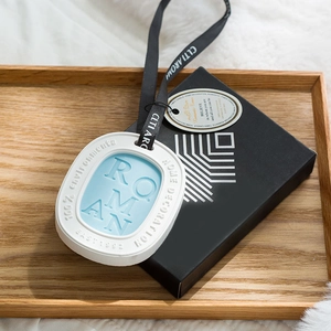 Blue and white oval aromatherapy wax tablet with black ribbon on a wooden tray