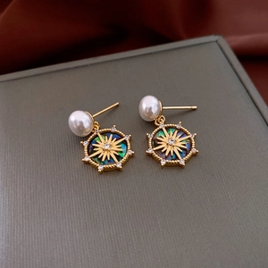 Macro detail of 18k gold plated sunburst pearl earrings on elegant silk fabric background