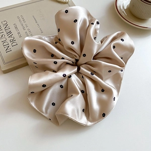 Gros plan du chouchou en satin champagne avec motif floral et bordure en dentelle