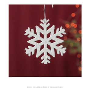 Close-up of a white glitter snowflake ornament with silver string on a red festive background