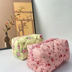 Quilted cotton makeup bags with floral patterns and pink zippers in a cozy home setting