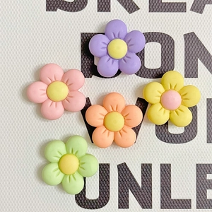 Macro shot of colorful matte resin five-petal flower charms for DIY crafts and accessories