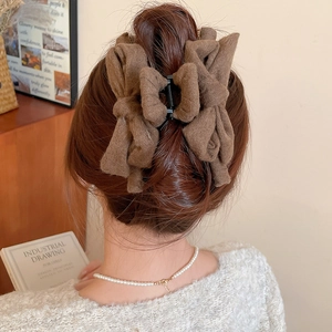 Macro detail of an elegant coffee brown fabric bow hair claw clip styled on long hair