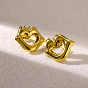 Macro view of gold lip-shaped stud earrings with heart cutout and polished finish